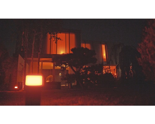 Verlichte tuin met modern huis op de achtergrond.