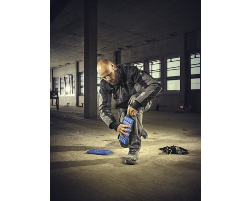 Een man bevestigt kniebeschermers aan zijn been op een bouwplaats