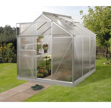 Kas met planken en planten in de tuin.