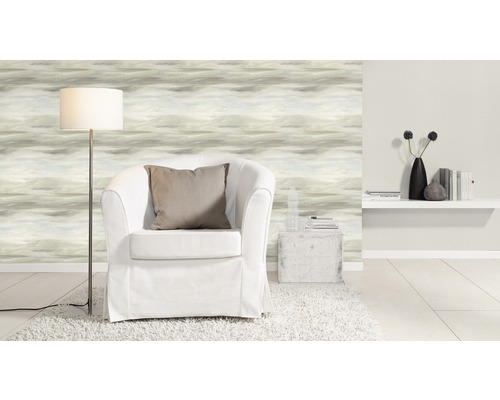 Woonkamer met fauteuil, staande lamp, patroonbehang en decoraties op een plank