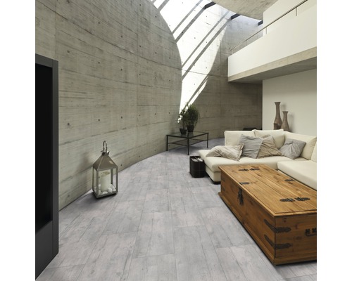 Lichte woonkamer met betonnen plafond, betonnen muur, bank en houten vloer in plankenlook.