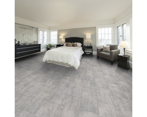 Slaapkamer met grijze houten vloer, bed, commode en fauteuil