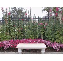 Tuinlandschap met bank, bloemen en hek
