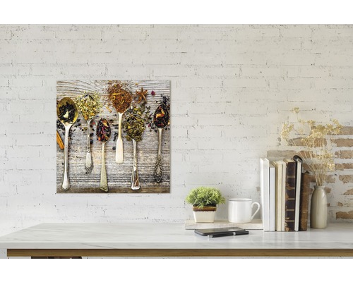 Decoratieve plaat met verschillende theesoorten in lepels op een houten achtergrond