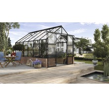 Glazen kas met bakstenen fundering in de tuin