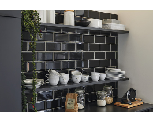 Keukenscène met zwarte metrotegels, planken en keukengerei