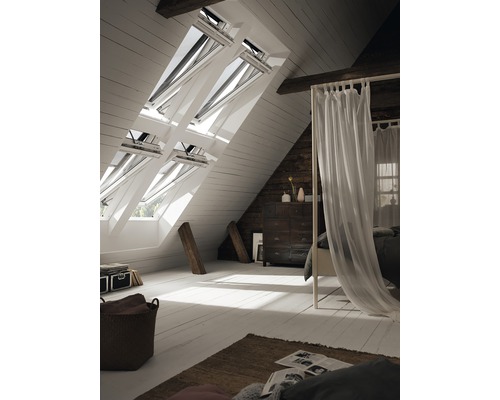 Lichte zolderkamer met dakramen, bed en commode