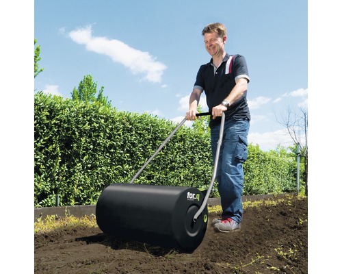 Een man gebruikt een gazonrol van for.q in de tuin.