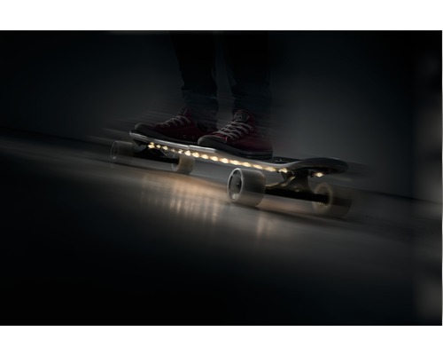 Persoon op een rijdend skateboard met ledverlichting.