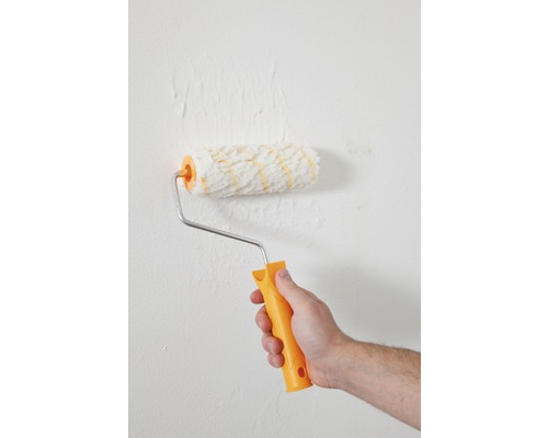 Een persoon schildert een muur met een verfroller.