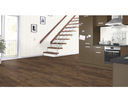 Interieur met bruine laminaatvloer, trap, keuken en balkondeur.
