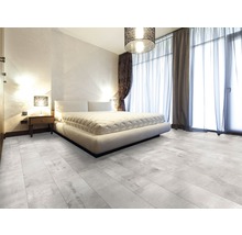 Lichte slaapkamer met tweepersoonsbed, nachtkastje, gordijnen en vloertegels met houtlook.