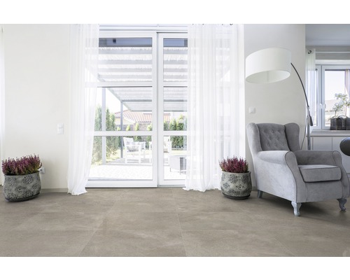 Lichte woonkamer met vloertegels, fauteuil, planten en openslaande deuren