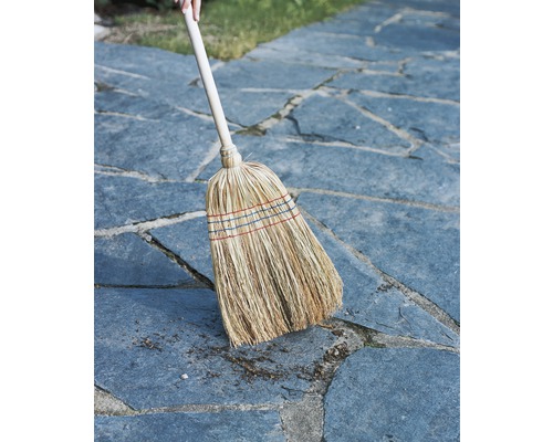 Strooien bezem met houten steel op straatstenen