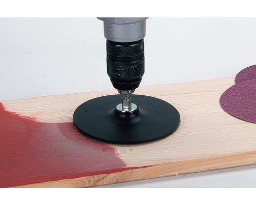 Boormachine met schuurschijfopzetstuk op houten plank