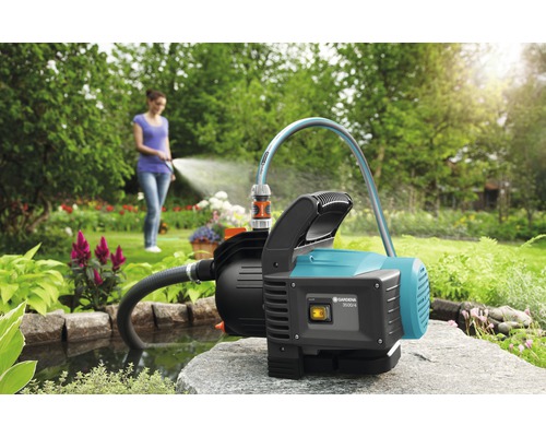 Tuin met vijver en een vrouw bewaterd met een tuinpomp