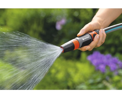 Een persoon houdt een tuinslang met waterstraal in de hand