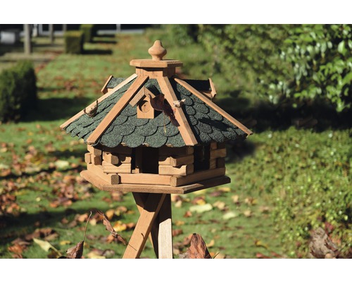 Houten vogelhuis met standaard in de tuin.