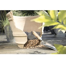 Beschadigde terracotta plantenpot met kleikorrels en plantschep