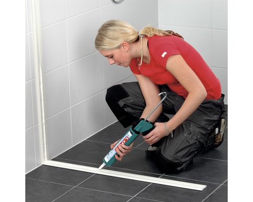 Vrouw dicht douche af met afdichtmiddel en kitpistool in de badkamer