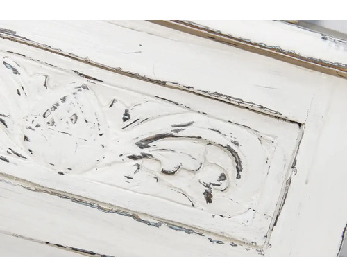 Detail van een wit houten meubel met snijwerk