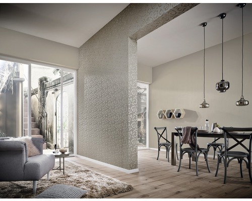 Woonkamer met behang, eettafel en stoelen, en een zithoek met fauteuil