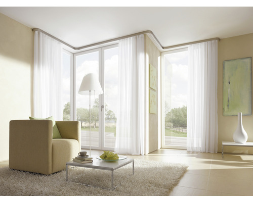 Lichte woonkamer met fauteuil, vloerkleed en witte gordijnen voor ramen