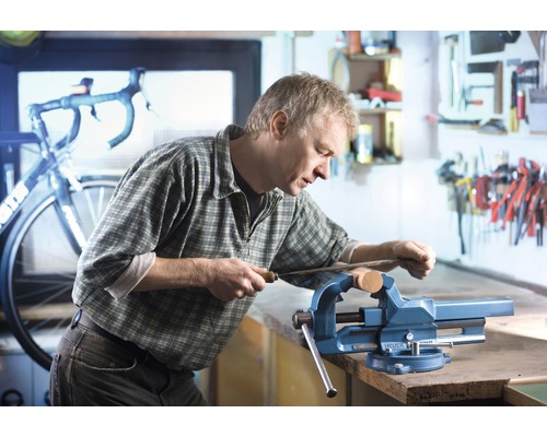 Man werkt met een vijl aan een werkstuk dat in een bankschroef is vastgeklemd.