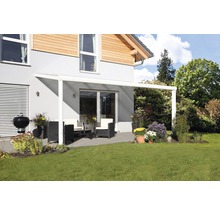 Terras met terrasoverkapping, tuinmeubelen en barbecue op een gazon voor een woonhuis