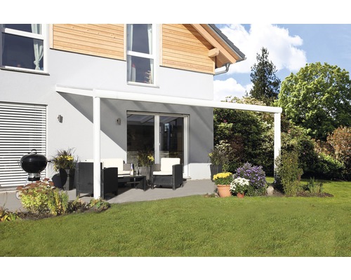 Terras met terrasoverkapping, tuinmeubelen en barbecue op een gazon voor een woonhuis