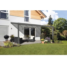 Terrasoverkapping met tuinmeubelen en barbecue op een gazon voor een huis