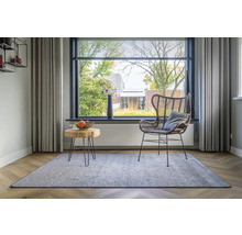 Woonkamer met vloerkleed, rotan stoel en houten tafel