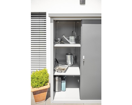 Tuinkast met schuifdeur en meerdere planken, gevuld met tuinaccessoires en barbecuegerei