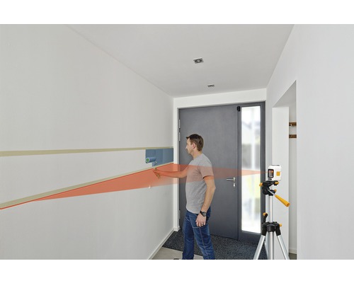 Man schildert muur met verfroller en laserwaterpas in hal