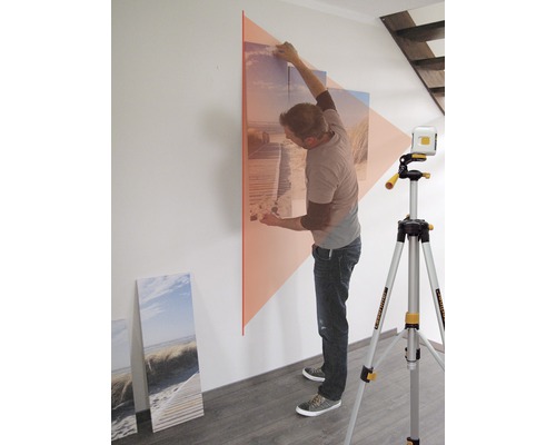Man richt met een lijnlaser een foto aan een muur uit.