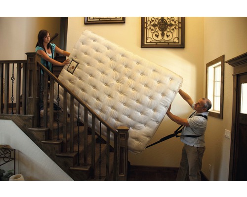 Twee mensen dragen een matras de trap op