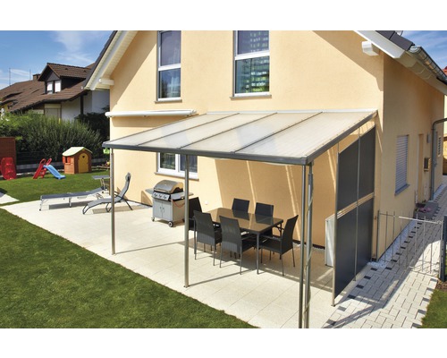 Overdekt terras met eettafel, barbecue en ligstoel in de tuin.