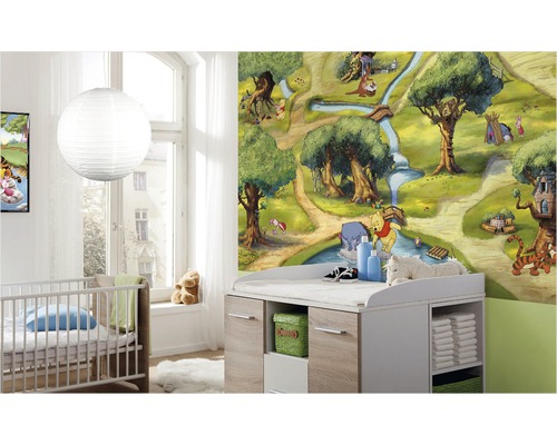 Kinderkamer met Winnie de Poeh behang, babybed en commode voor babyuitrusting.
