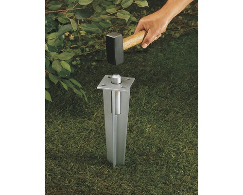 Metalen inslagpaalhouder wordt met een hamer in de grond geslagen.