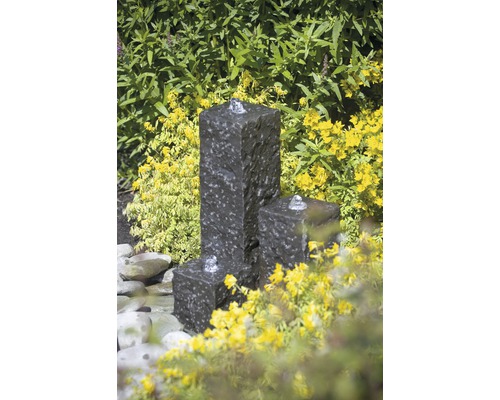 Decoratieve tuin fontein met drie spuitmonden en omliggende planten