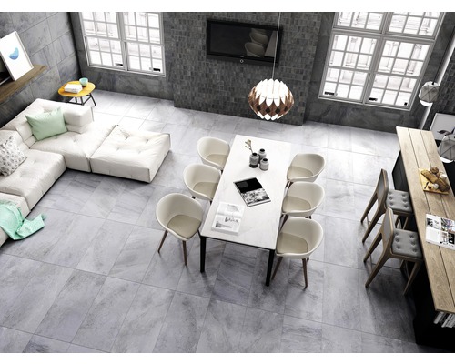 Lichte woonkamer met tegelvloer, zithoek, eettafel en kitchenette.