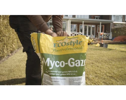 Een persoon opent een pak EcoStyle Myco-Gazon gazonmeststof NPK 8-3-6