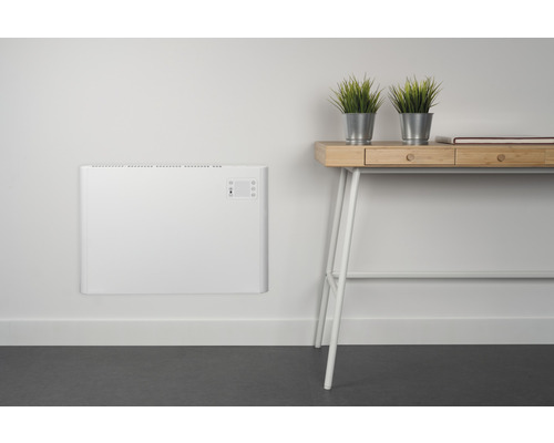 Aan de muur gemonteerde radiator naast een bureau met decoratieve planten.