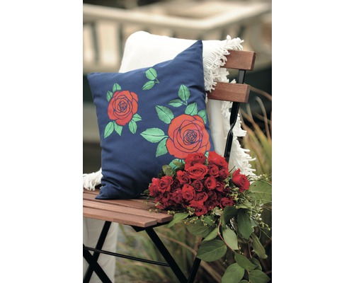 Decoratief kussen met rozenmotief op een stoel met een boeket bloemen