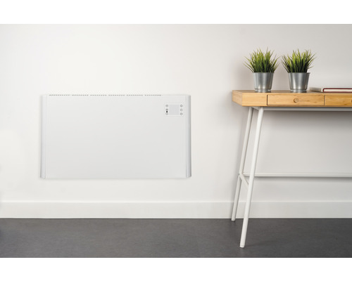 Wandgemonteerde, witte radiator naast een bureau met planten