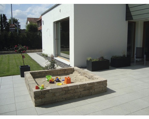 Buitenkant met zandbak, plantenbakken en terras