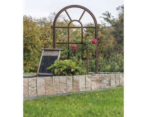 Decoratieve tuin met metalen raamkozijn, wasbord en stenen muur.