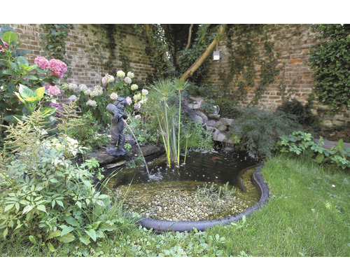 Vijver met een sculptuur van een jongen met een kruik in een tuin