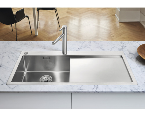 Roestvrijstalen spoelbak met afdruiprek en kraan op een marmeren werkblad.