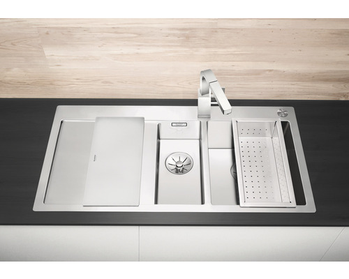 Roestvrijstalen spoelbak met afdruiprek, snijplank en kraan op een aanrecht.